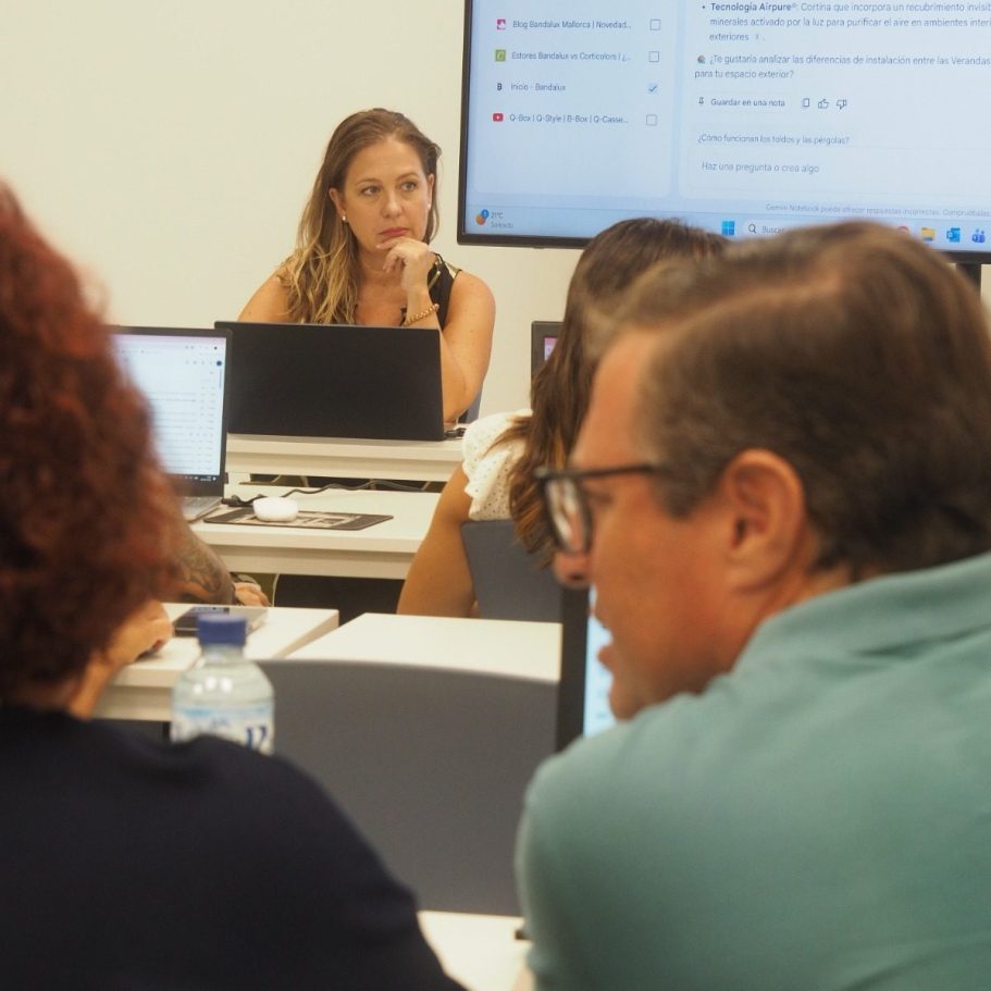 Curso de LinkedIn Mujer frente a un grupo, levantando la mano mientras los demás participan activamente.